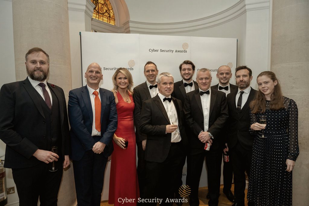 Guests in black tie at the Cyber Security Awards ceremony, gathered at the awards backdrop